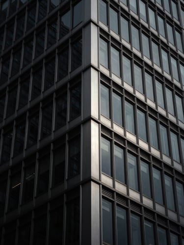 Moody architectural photography of a modern steel and glass skyscraper corner, low-key dramatic lighting, deep charcoal and brushed silver tones, high contrast, 35mm