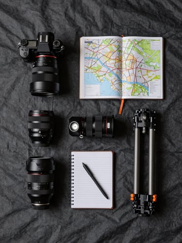 Overhead flat-lay of expedition gear laid out on a tarp — camera body, lenses, field notebook, topographic map, headlamp, and compact tripod arranged in operational sequence, charcoal canvas surface, harsh directional light from one side, no people