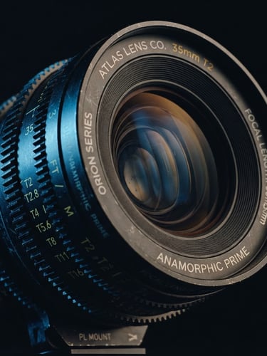Extreme close-up of a high-end digital anamorphic cinema lens, low-key dramatic side-lighting, deep shadows, cool blue and amber tones, 35mm.