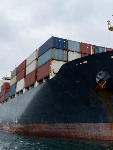 Low-angle high-contrast shot of a massive deepwater container vessel docked at an industrial terminal, overcast maritime sky, steel hulls.