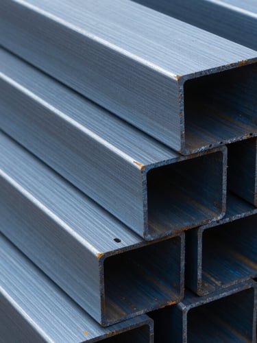 Extreme close-up of heavy industrial steel billets stacked in a yard, cold metallic blue tones, high contrast lighting on brushed textures