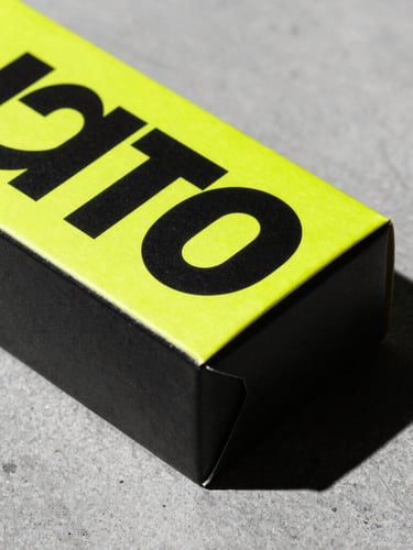 Bold graphic design mockup of a packaging box with neon yellow accents, sharp shadows on a concrete background, high-contrast studio lighting, 35mm
