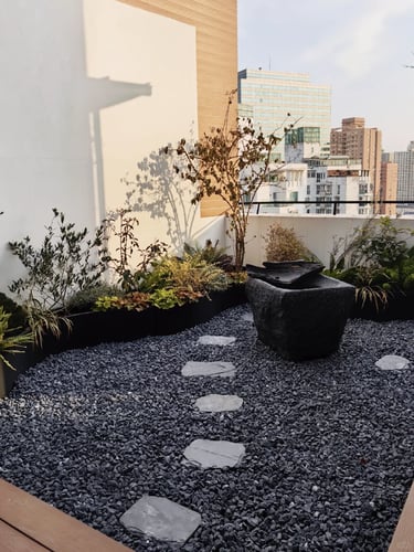 Small rooftop garden with dark gravel, stepping stones, planters, and a simple modern material palet