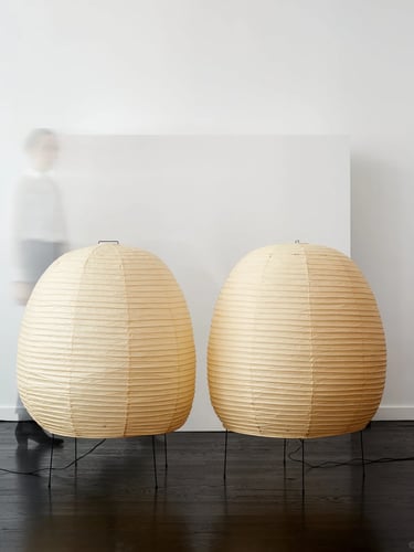 Two warm Akari paper lamps with rounded shapes, creating gentle diffused light in a calm modern inte