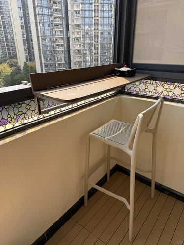 Narrow balcony with folding furniture, vertical plants, and warm lighting for a comfortable small ou