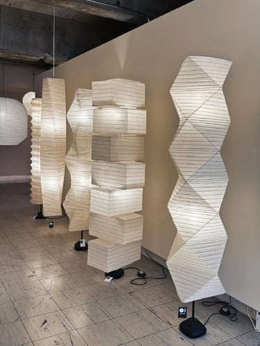 Sculptural white paper lamps with geometric forms, reflecting Isamu Noguchi’s quiet lighting design