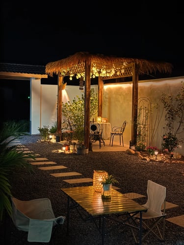 Cozy garden seating spot at night with warm lighting, outdoor chairs, a small table and a peaceful r