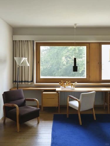 Calm living room with armchairs, large window and soft natural light showing warm Nordic modern desi