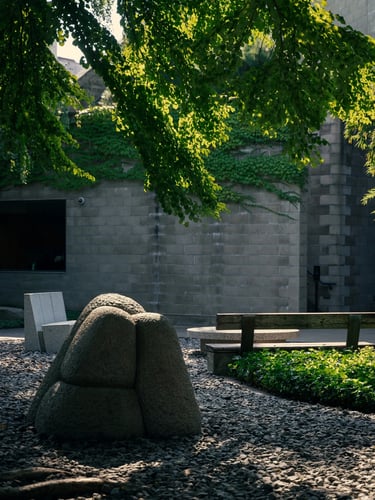 Outdoor stone sculpture surrounded by trees and natural shade, showing Noguchi’s connection to lands