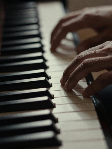 Macro close-up of hands resting on ivory piano keys, high-contrast chiaroscuro lighting, deep shadows, desaturated monochrome tones, 35mm film grain.