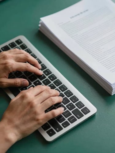 Top-down view of hands typing on a slim keyboard next to a neat stack of documents, warm side lighting, clean workspace aesthetic, green and blue accents.