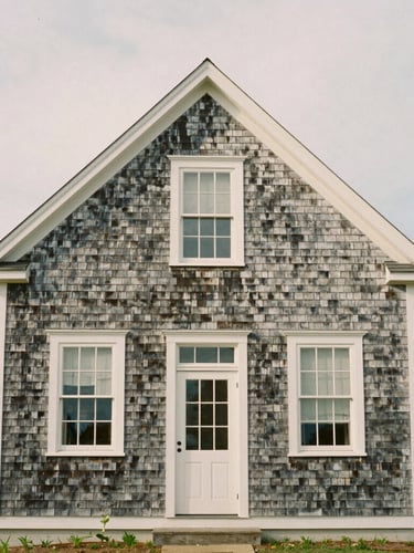 Straight-on architectural elevation of a weathered cedar shingle home on the Guilford coast, soft overcast daylight, medium format film
