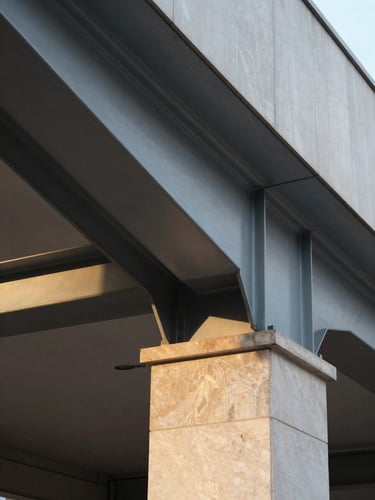A perfectly level, architectural close-up of a structural steel cantilever meeting a honed stone column, cast in crisp morning light, showing clean geometric lines.