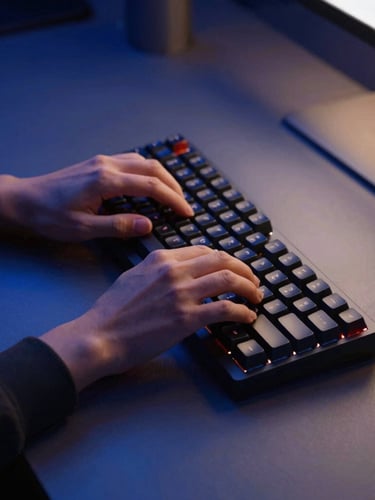 A clean modern workspace with hands typing on a mechanical keyboard, low-key dramatic lighting with deep blue shadows and warm amber highlights, 35mm focus