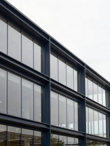Wide shot of a modern, clean-lined corporate office interior, focus on structural steel and glass, soft overcast daylight, muted navy and champagne gold tones, sharp focus, 35mm lens.