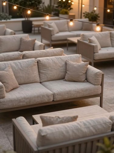 Overhead shot of a beautifully organized outdoor lounge area with neutral-toned linen sofas under glowing string lights at dusk.
