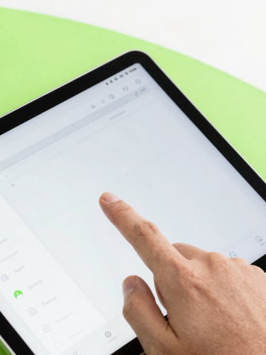 Close-up of a hand interacting with a modern Android tablet displaying a wireframe of an app interface, bright studio light, green accents, 50mm