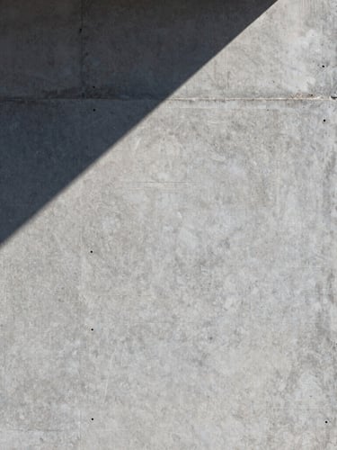 Close-up of pristine acrylic render texture on a concrete wall, sharp morning light casting clean geometric shadows, architectural detail.