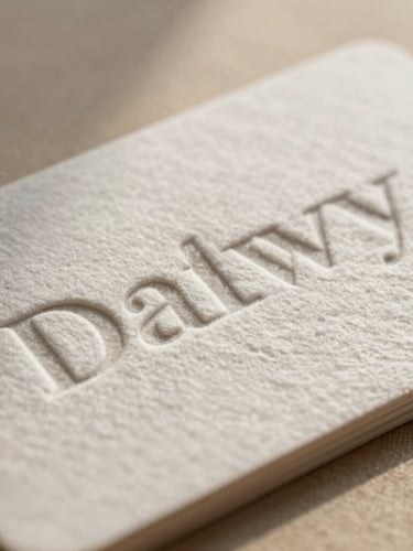 Extreme close-up of heavy cotton business card with deeply embossed minimalist serif typography, soft side-lit shadow on textured warm beige linen