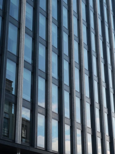 Façade de bâtiment moderne aux lignes épurées, de grands vitrages teintés reflétant un ciel bleu pur avec une clarté optique parfaite