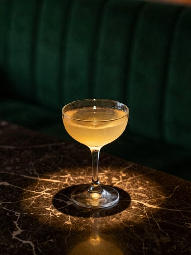 Moody editorial close-up of a classic cocktail on a dark marble counter under a single warm spotlight, rich shadows, deep green ambient background