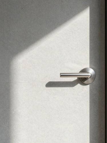 Straight-on architectural shot of a clean, minimalist modern Swiss concrete entryway with a brushed steel door handle, bright morning daylight, soft natural shadows.