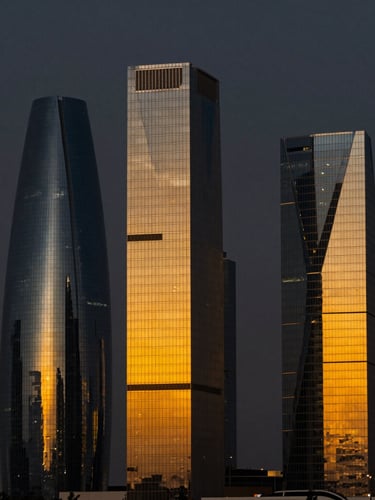 Sleek architectural shot of Riyadh financial district at dusk, sharp golden-orange light reflecting off modern glass skyscrapers, 35mm corporate photography, dramatic dark background.