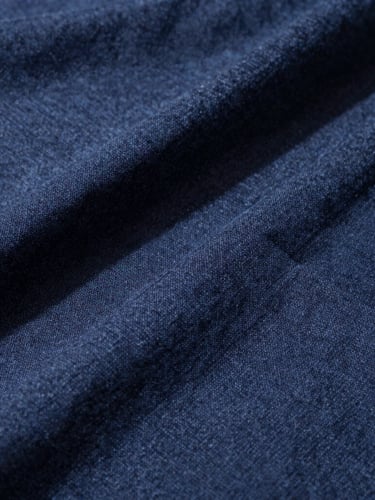 Close-up of heavy linen fabric grain with high-contrast side daylight casting deep shadows on structural seams, 35mm photography