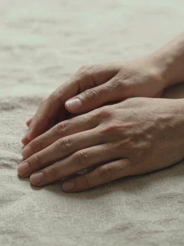 Close-up of hands resting gently on a textured linen fabric, soft diffused overcast daylight, cinematic grain, warm editorial tones.
