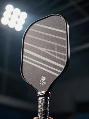 Dynamic low-angle shot looking up at a custom-designed pickleball paddle against crisp indoor stadium floodlights, sharp geometric shadows.