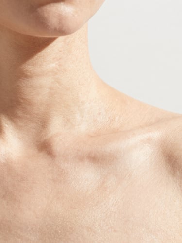 Minimalist editorial photo of clean skin with natural texture under bright, high-key natural sunlight, sharp shadows, 35mm lens