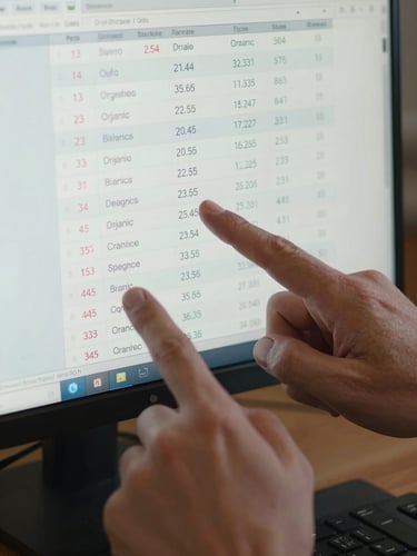 Tight close-up overhead of hands pointing at a monitor showing a search-ranking report with keyword positions and organic traffic numbers climbing, cool bright even studio lighting, dark keyboard edge visible at bottom
