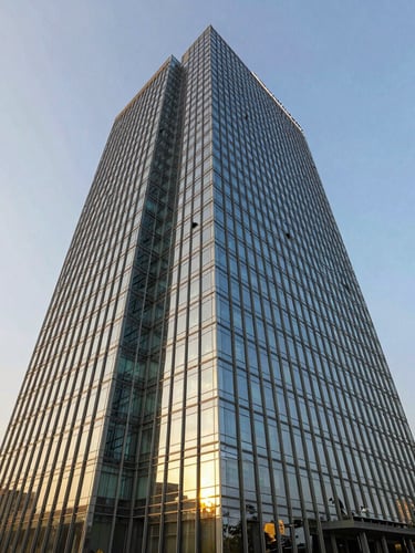 Wide-angle architectural photography of modern glass office tower in Gurugram under bright natural golden-hour sunlight, sharp focus