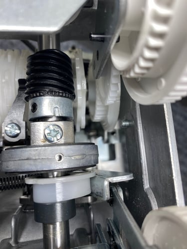 Close-up of the gears and other moving metal and plastic parts inside a sewing machine. 