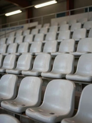 Close-up of freshly cleaned stadium seating rows under flat overhead fluorescent light, uniform surface finish visible across each seat back, no occupants, tight environmental framing