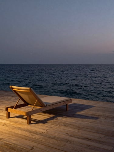 A vertical frame of a minimalist overwater villa deck at dusk, raw teak planks kissing the calm dark ocean, no people, single linen lounge chair, low golden light.