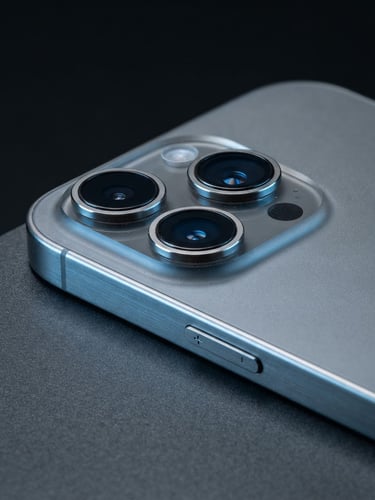 Sharp macro product shot of a pristine titanium iPhone reflecting cool blue and metallic studio light, clean dark background