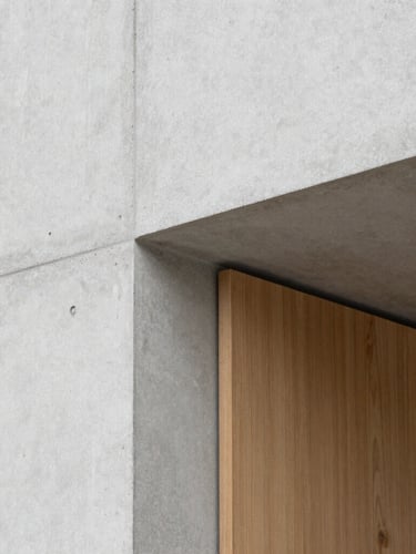 Close-up of a minimalist architectural detail, raw light gray concrete meeting a warm oak wooden panel, clean lines, soft natural overhead lighting, 35mm lens