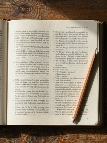 Top-down flat lay of an open scripture workbook on a rustic wooden table, soft morning light casting gentle shadows, a sharp wooden pencil resting on the thick cream paper.