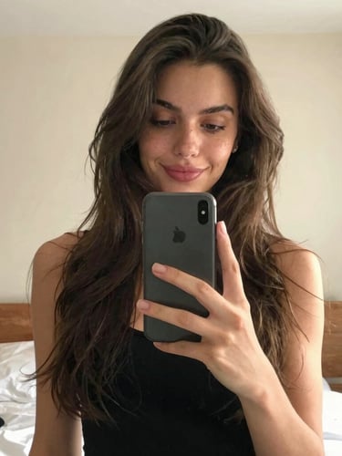 A casual mirror selfie of a beautiful French woman in her bedroom, natural warm lighting, holding a smartphone, realistic smartphone camera aesthetic