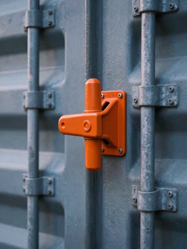Close-up of a heavy steel cargo container locking mechanism with a bright orange security seal, crisp industrial details, cool twilight lighting.