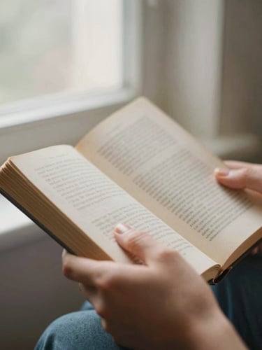 Close-up of hands holding a worn book during a quiet moment of prayer, soft natural daylight, muted earth tones, 35mm film.