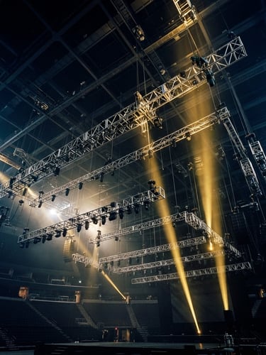 Extreme wide-angle shot of massive stage rigging and steel truss structures suspended from a dark arena ceiling, dramatic golden spotlights cutting through haze, 35mm photography