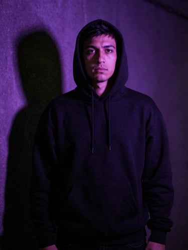Cinematic portrait of an Anderlecht supporter in a dark alley at night, dramatic purple backlighting, intense shadow, wearing a heavy-weight black hoodie, 35mm