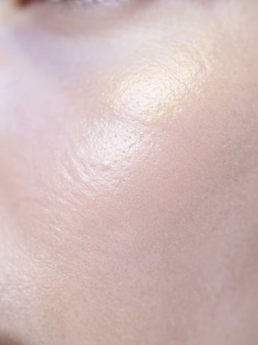 Macro studio photography of elegant skin texture under bright high-key light, soft gold reflections, clean and clinical depth of field.