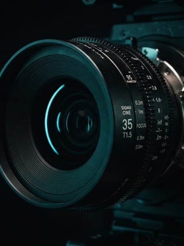 Extreme close-up of a high-end cinema camera lens, dramatic low-key studio lighting with a sharp cyan neon accent reflecting off the glass, deep shadows, 35mm lens