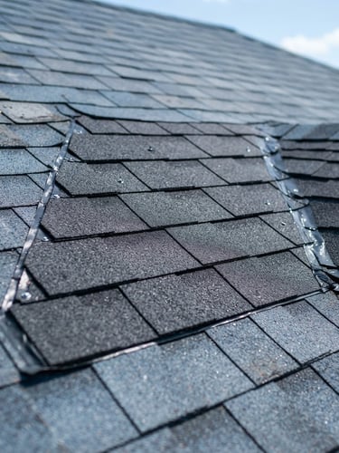 Crisp close-up of a clean shingle repair detail on a residential roof, bright Texas daylight, deep blue and slate gray tones, 50mm lens, professional craftsmanship visible.