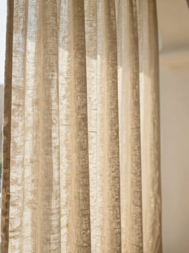A close-up of premium linen curtain folds catching warm natural sunlight streaming through a Riyadh villa window, architectural framing, soft sand tones, 35mm