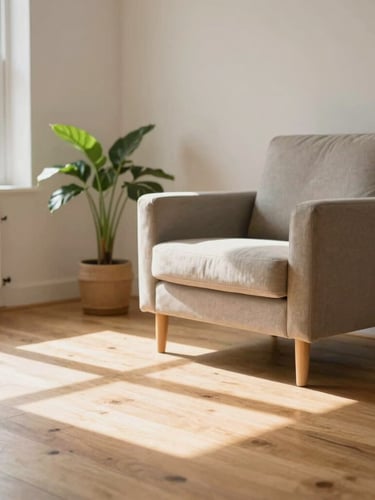 Bright, clean interior of a modern residential living room in Birmingham, soft natural daylight spilling across a wooden floor, a comfortable armchair, and a potted plant in the corner, warm and welcoming, shallow depth of field.