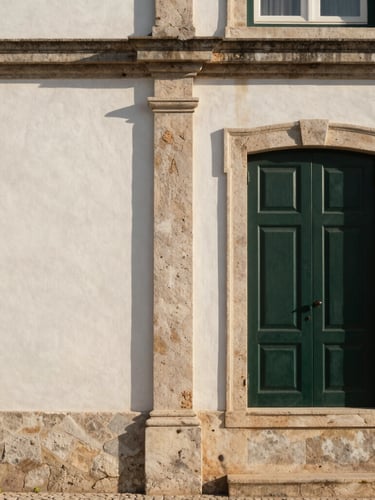 Architectural detail of a traditional Portuguese stone building facade in soft late-afternoon sun, clean lines, elegant shadows, negative space on the left